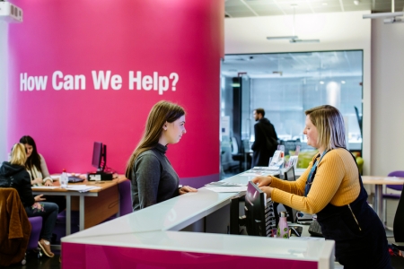 Female student standing at careers and employability help desk