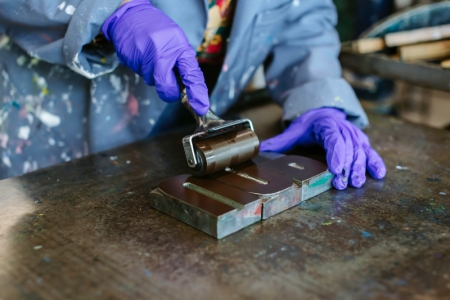 A person with gloves using a letterpress