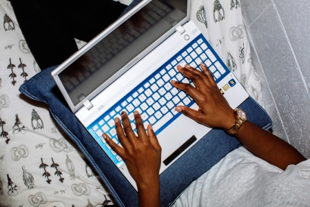 Student using laptop to complete university work in halls bedroom