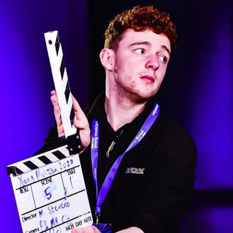 Student standing with clapperboard