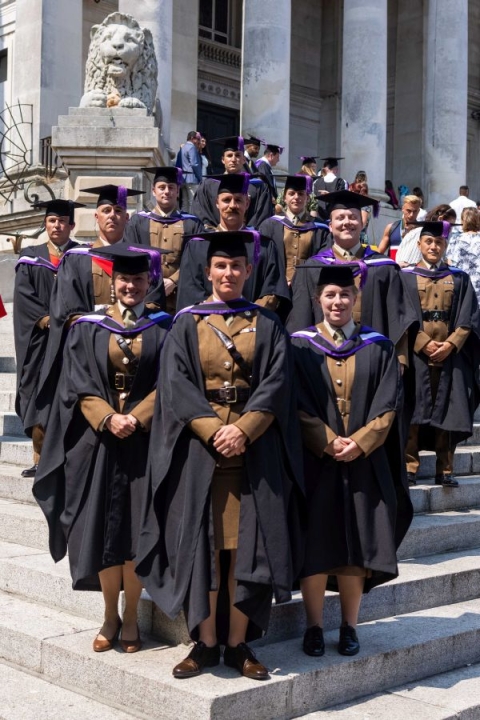 Group of Army soldiers wearing gowns and mortarboards on their graduation day